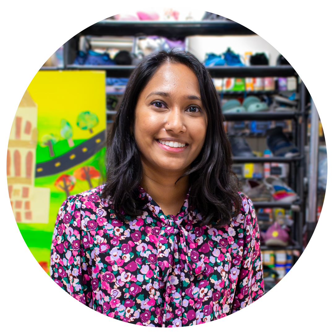 Woman smiling with shelves of clothing and hygiene items.
