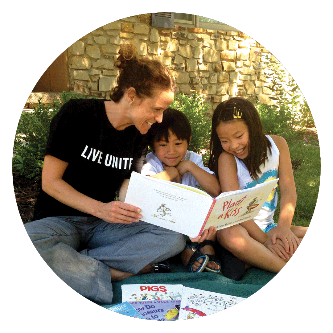 White woman reading to two Asian children.