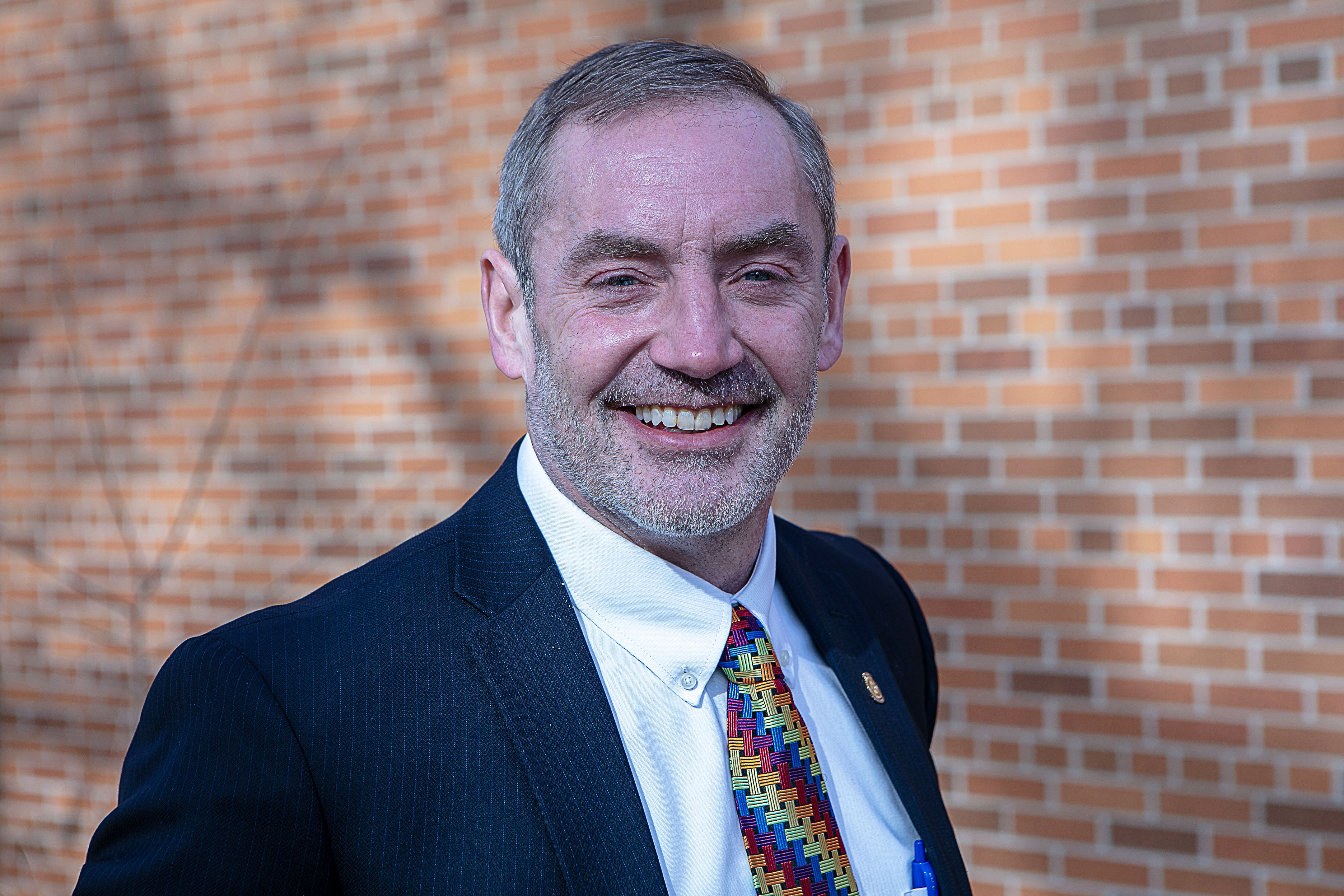 White man in suit smiling.