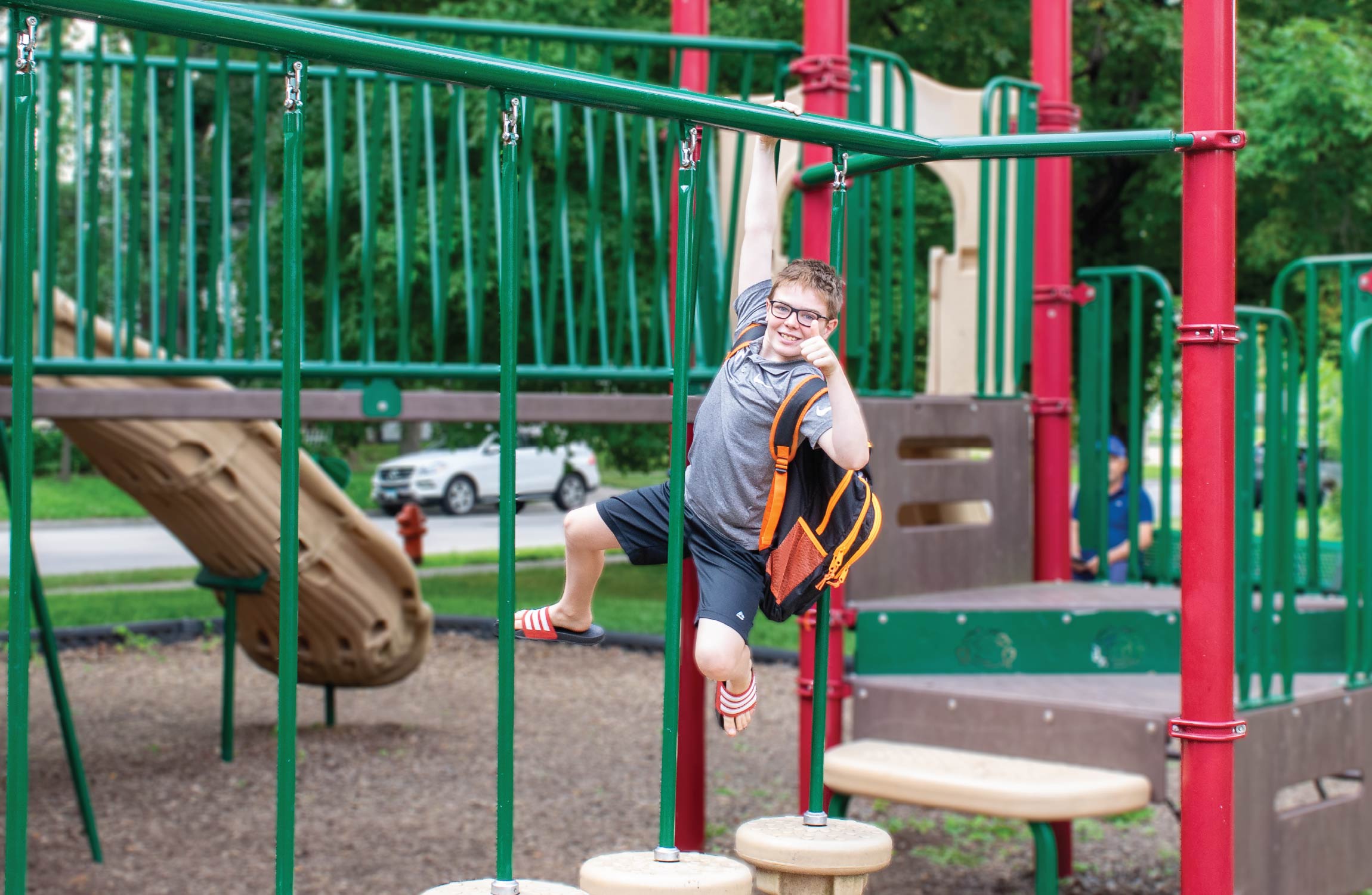 Young boy with backpack on playground.