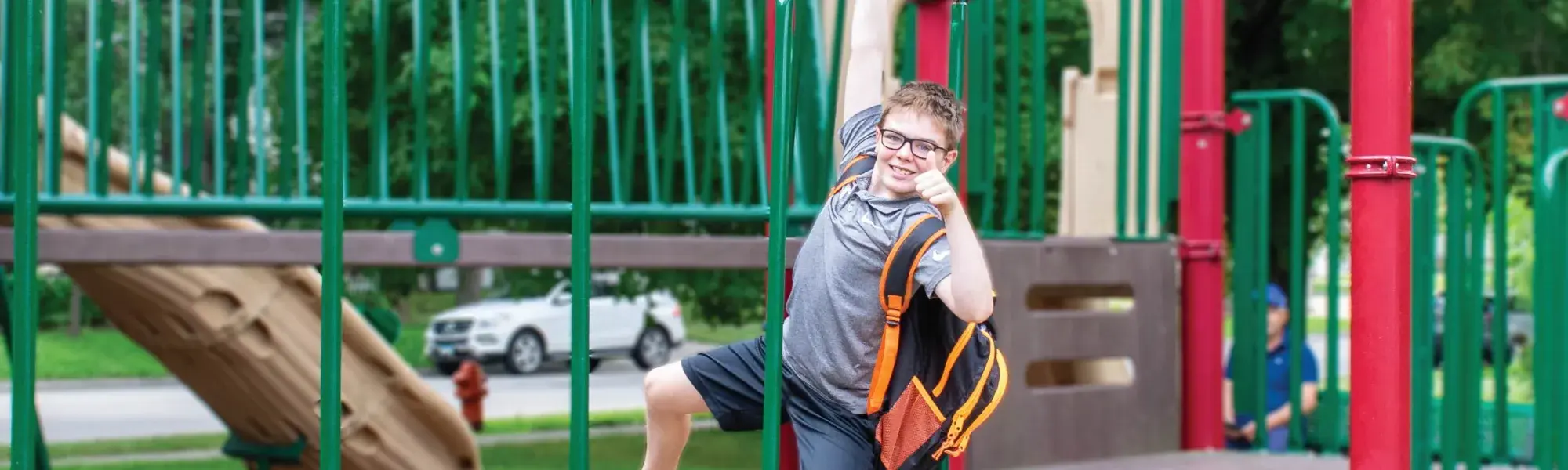 Young boy with backpack on playground.
