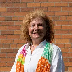 A smiling white woman in front of a brick wall
