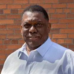 Photo of a smiling black man in front of a brick wall
